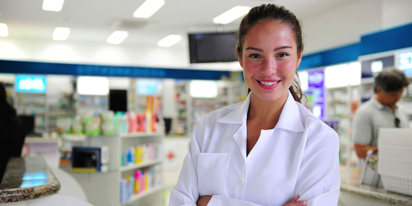 Woman in White coat standing in front of a pharmacy counter