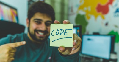 Person holding a sticky note that says code