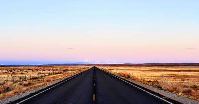 Two lane road with mountains and moonrise in the distance