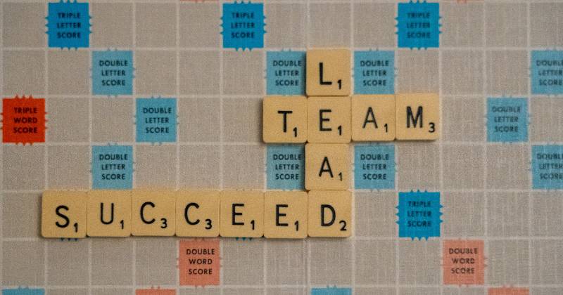 Scrabble tiles on gameboard with Leader, Team, and Success showing